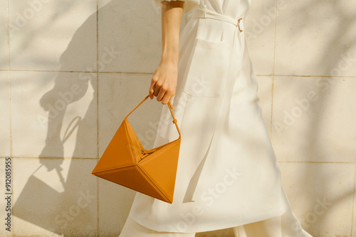 Elegant Woman Holding Geometric Handbag Against Neutral Backgrou photo