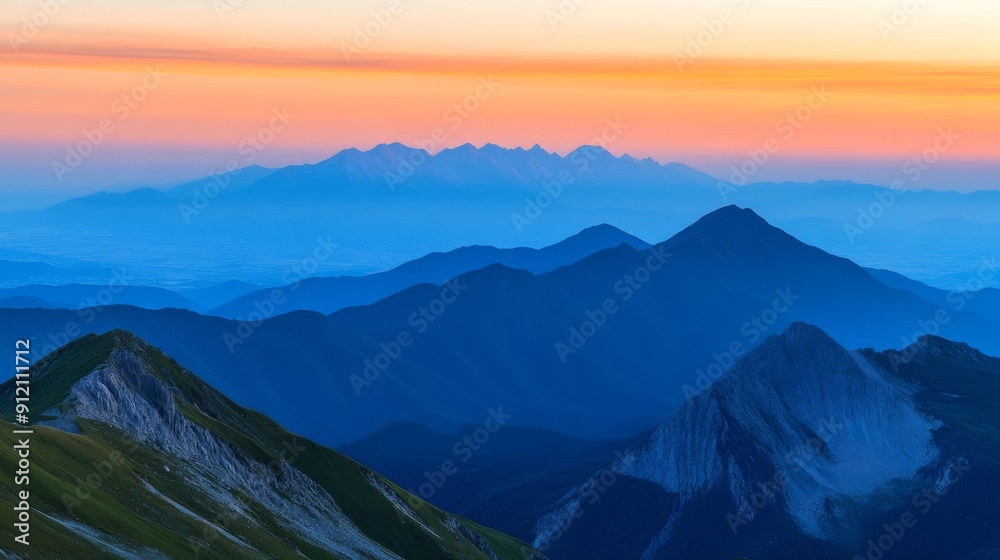 Obraz premium A panoramic view of a majestic mountain range during sunset with layers of colors in the sky and a serene valley below capturing the aweinspiring beauty of the natural landscape