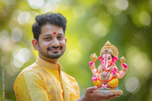 Young indian man in traditional wear holding lord ganesha sculpture in hand photo