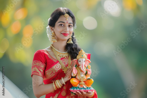 Young indian woman in red color saree holding lord ganesha sculpture photo