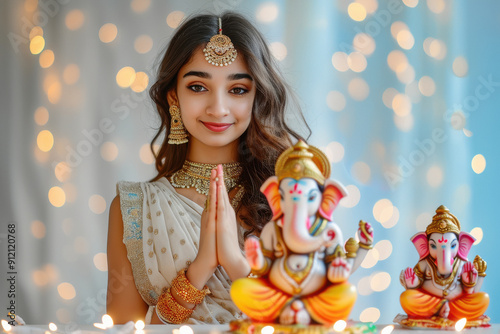 young Indian woman wearing cream colour dress and prayer, and side table a big colourful and beautiful lord Ganesha statue. photo