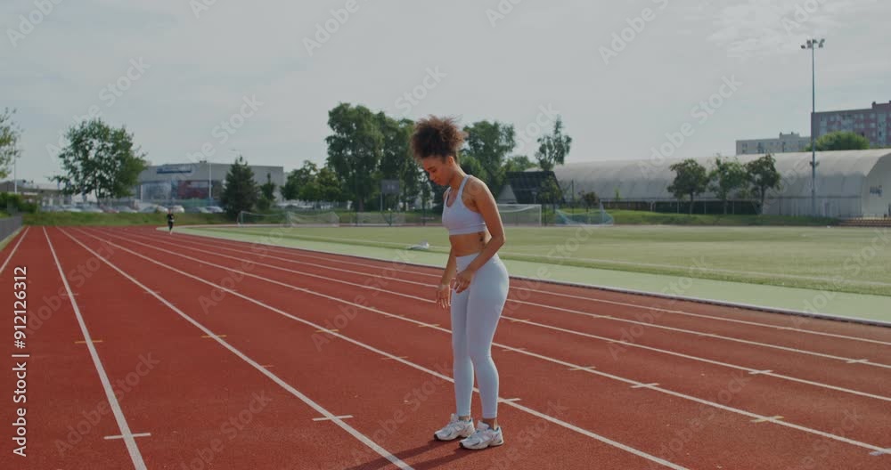 A woman in sports clothes does exercises standing at the city stadium on a summer day A woman in sports clothes does exercises standing at the city stadium on a summer day