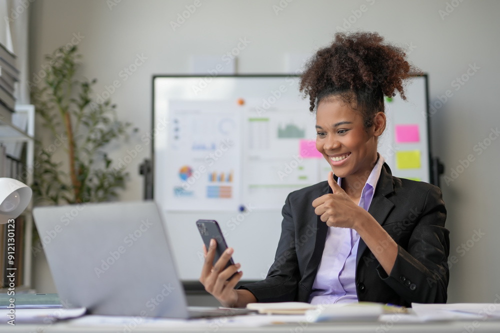 Smiling businesswoman is showing a thumbs up gesture while looking at her smartphone Smiling businesswoman is showing a thumbs up gesture while looking at her smartphone