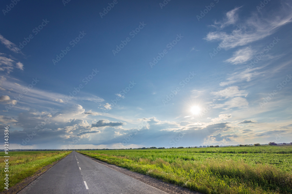 A long road with a clear blue sky and a few clouds A long road with a clear blue sky and a few clouds