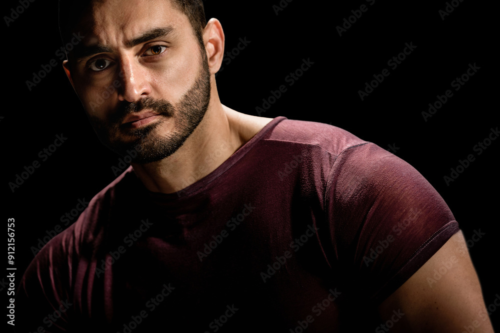 Dramatic portrait of strong brutal man with serious look, Dramatic allure: Young man's low-key portrait exudes intensity with a dark setting Dramatic portrait of strong brutal man with serious look, Dramatic allure: Young man's low-key portrait exudes intensity with a dark setting