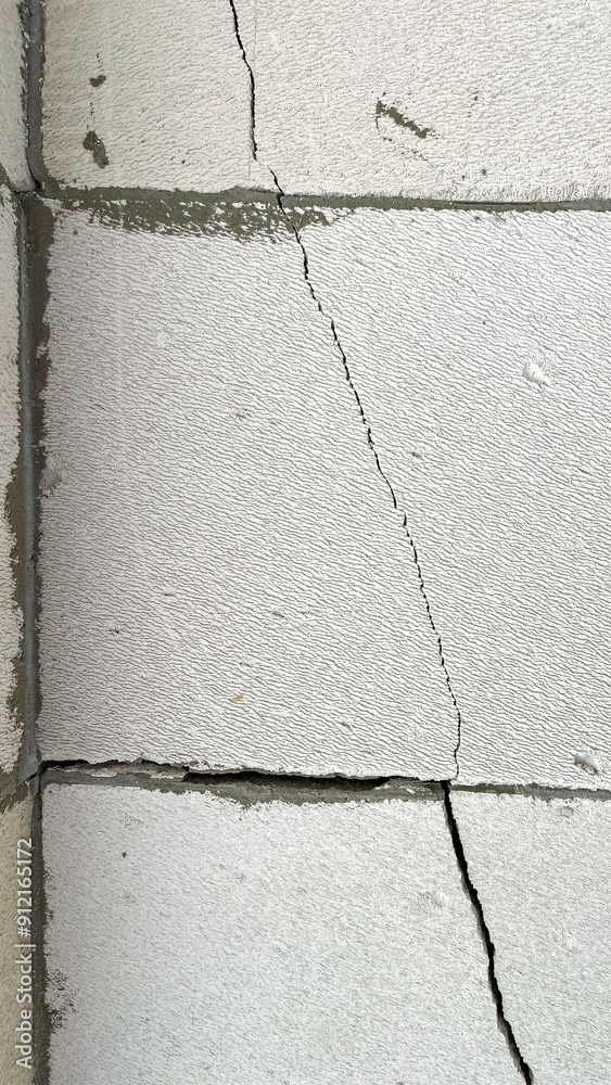 Obraz premium a crack in gas block wall, defective wall, cracked masonry, Cracks on wall, Low-quality brickwork, subsidence and cracking in wall.