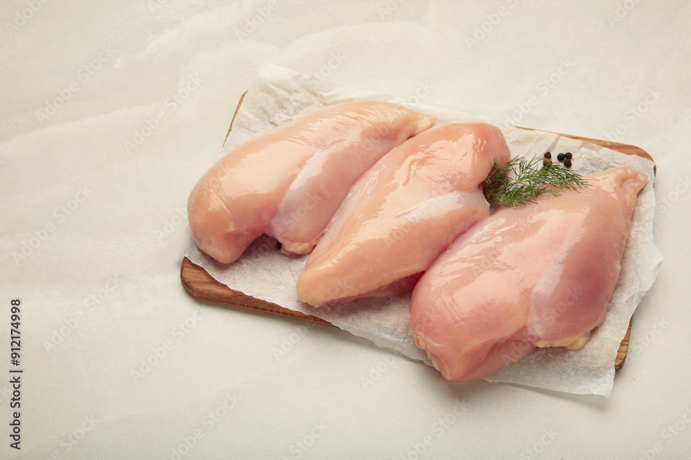 Raw chicken fillet on a cutting board on light background. Top view Raw chicken fillet on a cutting board on light background. Top view