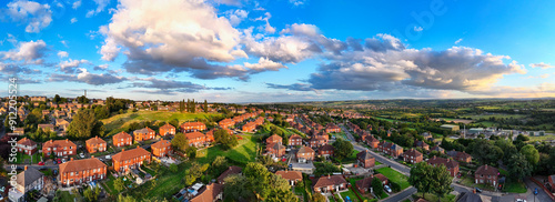 Panorama aerial drone photography of a summer evening in a typical urban town scene in the town of Dewsbury moor, west Yorkshire UK. Showing industrial chemical plant, red brick council housing.