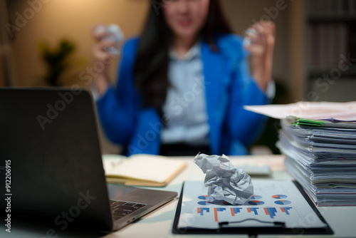 Angry Asian businesswoman or female office worker tearing and crumpling a broken document. Not correct as required Made a mistake while working at her desk. working overtime Office syndrome concept. photo