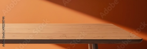 High-quality image of a smooth wooden table in a sunlit room with an orange wall, showcasing minimalist interior design.