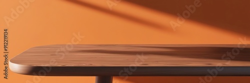 High-quality image of a smooth wooden table in a sunlit room with an orange wall, showcasing minimalist interior design.