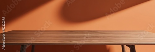 High-quality image of a smooth wooden table in a sunlit room with an orange wall, showcasing minimalist interior design.