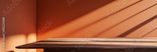 High-quality image of a smooth wooden table in a sunlit room with an orange wall, showcasing minimalist interior design.