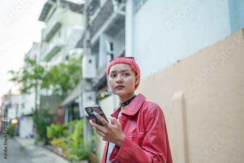 Traveler Gen z girl leather fashion with punk Asian woman tourist in city street searching location in map application online smart phone using GPS navigating