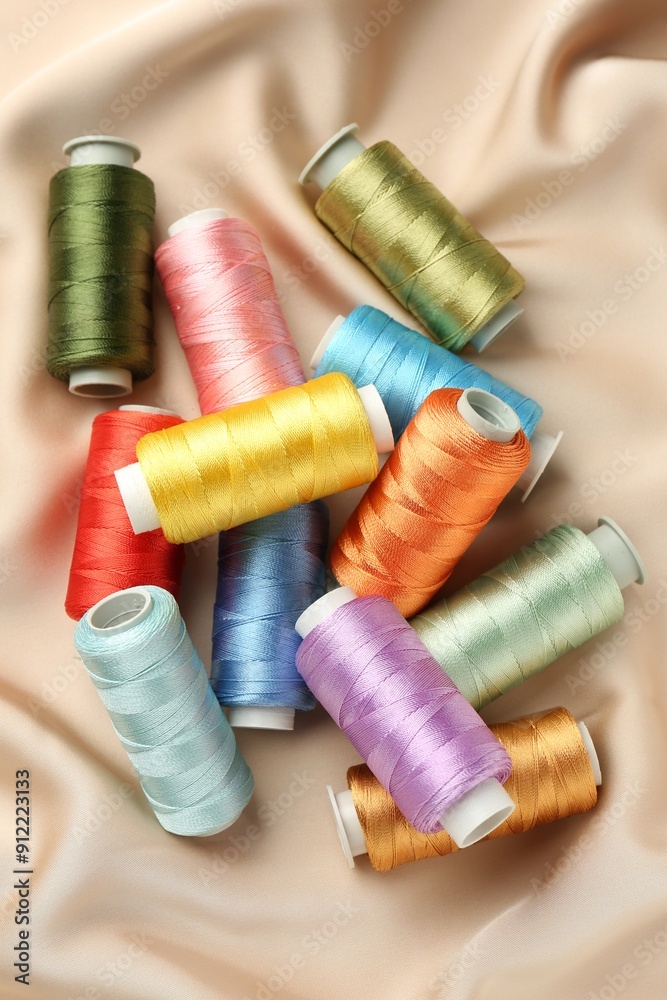 Spools of sewing threads on beige cloth, top view Spools of sewing threads on beige cloth, top view