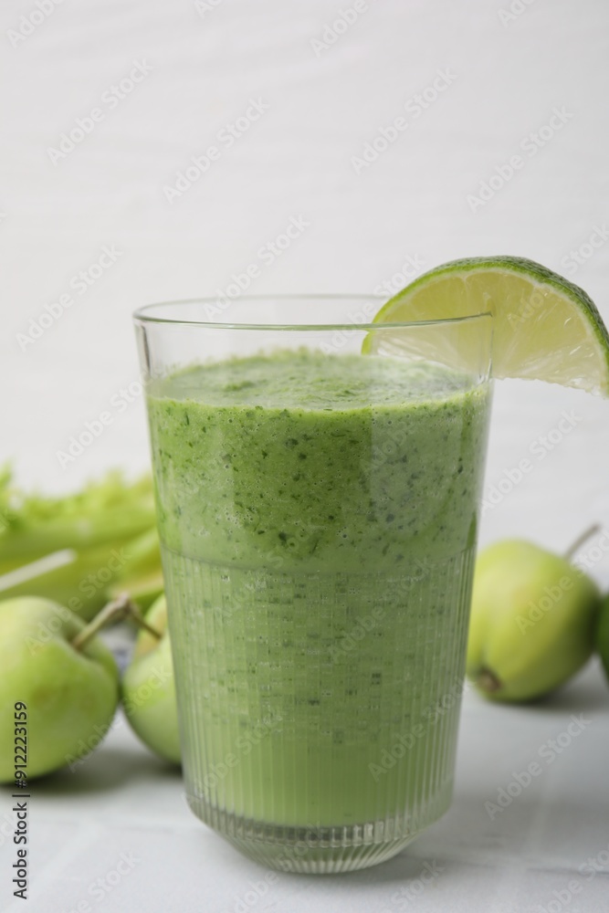 Tasty green smoothie in glass with lime and apples on white tiled table, closeup Tasty green smoothie in glass with lime and apples on white tiled table, closeup