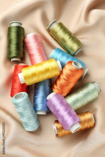 Spools of sewing threads on beige cloth, top view