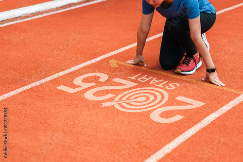 New year 2025 concept, beginning of success. Text 2025 written on asphalt road and male runner preparing for the new year. Concept of challenge or career path and change. photo