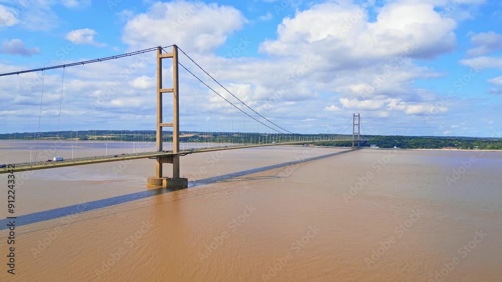 Aerial drone view of Humber Bridge, 12th largest suspension span, gracefully crossing River Humber, connecting Lincolnshire to Humberside with traffic. Aerial drone view of Humber Bridge, 12th largest suspension span, gracefully crossing River Humber, connecting Lincolnshire to Humberside with traffic.