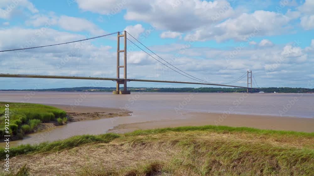 Aerial drone view of Humber Bridge, 12th largest suspension span, gracefully crossing River Humber, connecting Lincolnshire to Humberside with traffic. Aerial drone view of Humber Bridge, 12th largest suspension span, gracefully crossing River Humber, connecting Lincolnshire to Humberside with traffic.