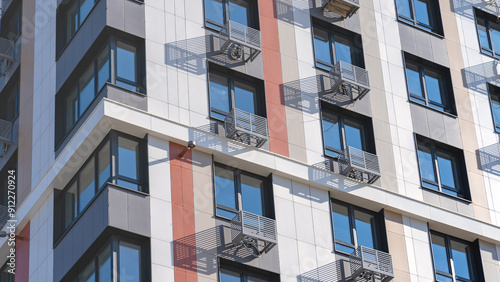 A tall building with a lot of windows and a rooftop antenna. The building is white and orange