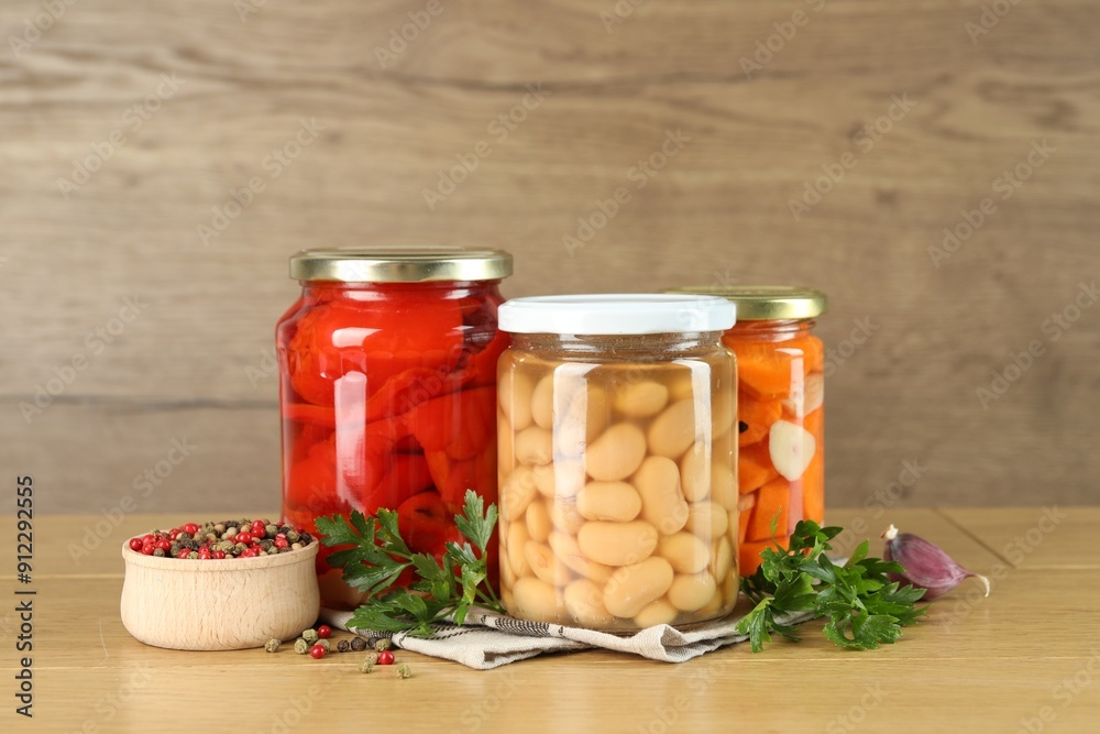 Different pickled products in jars and spices on wooden table Different pickled products in jars and spices on wooden table