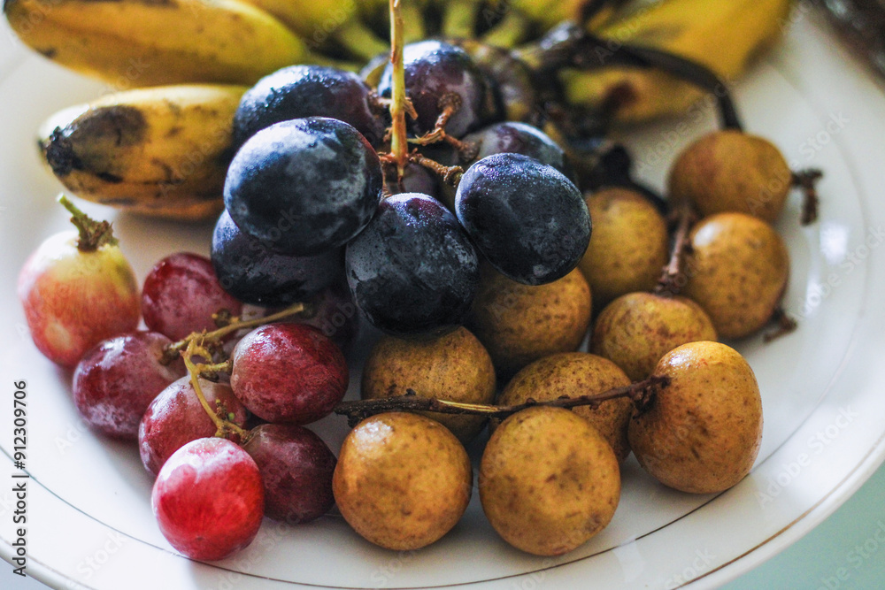 Fototapeta premium grapes, longans and bananas on plate