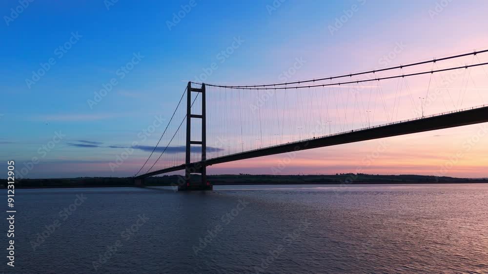 A picturesque spectacle unfolds as Humber Bridge stands adorned in the colors of the setting sun, with cars gracefully navigating its span. A picturesque spectacle unfolds as Humber Bridge stands adorned in the colors of the setting sun, with cars gracefully navigating its span.
