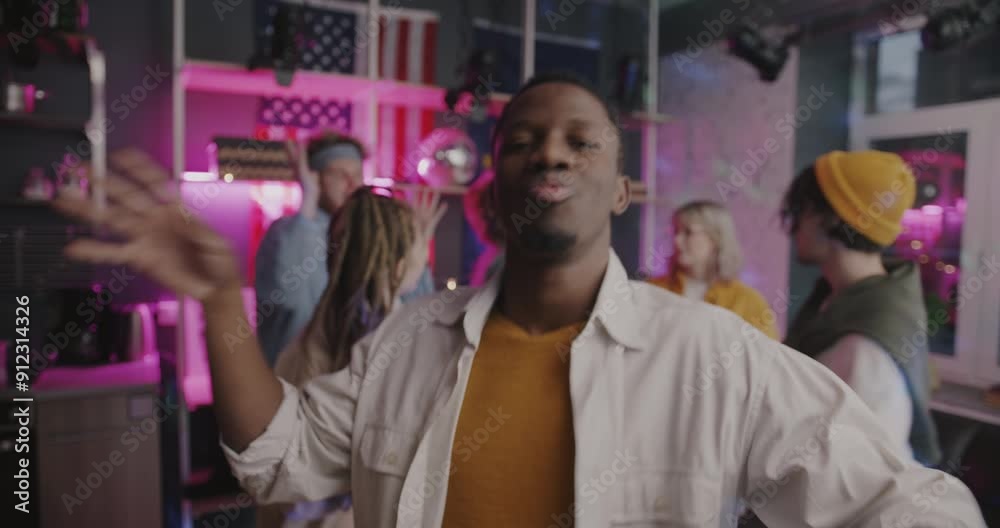 Portrait of carefree African American guy student dancing relaxing at night party with friends in illuminated house. Youth and entertainment concept. Portrait of carefree African American guy student dancing relaxing at night party with friends in illuminated house. Youth and entertainment concept.