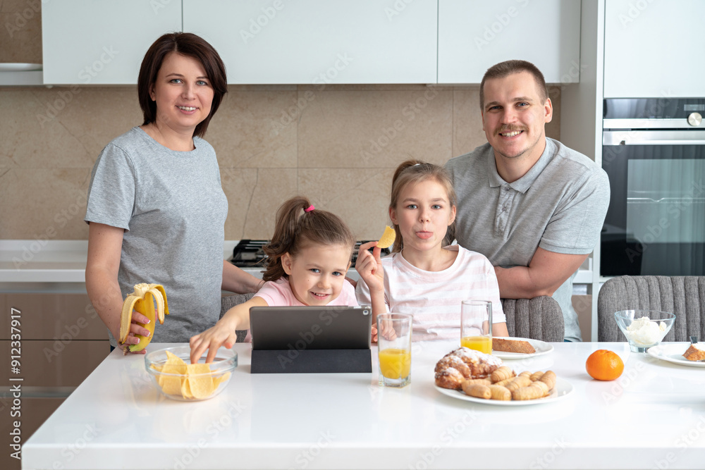 Smiling Family Dining Together at kitchen table and having fun, young parents with two daughters Smiling Family Dining Together at kitchen table and having fun, young parents with two daughters