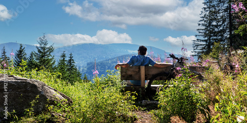 Radfahrer macht Pause auf einer Bank mit Blick auf den Feldberg im Schwarzwald