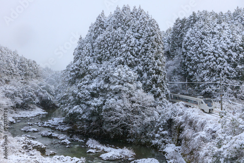 雪が積もる川代橋を福知山線の始発特急が通過する photo