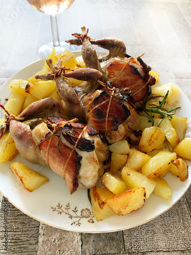 Quaglie al forno con patate ed erbe aromatiche sul tavolo. Copia spazio. direttamente sopra. photo