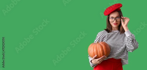 Pretty young woman holding pumpkin on green background with space for text
