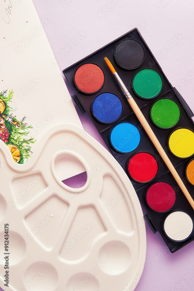 A white plastic palette with a watercolor palette with brush and a picture. Leisure activities and hobby theme A white plastic palette with a watercolor palette with brush and a picture. Leisure activities and hobby theme