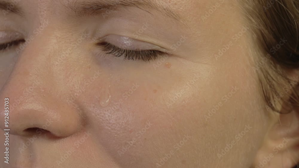 Close-up of a tear flowing down a woman's cheek, 4k resolution. Close-up of a tear flowing down a woman's cheek, 4k resolution.