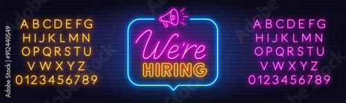 We Hiring neon sign in speech bubble on brick wall background.