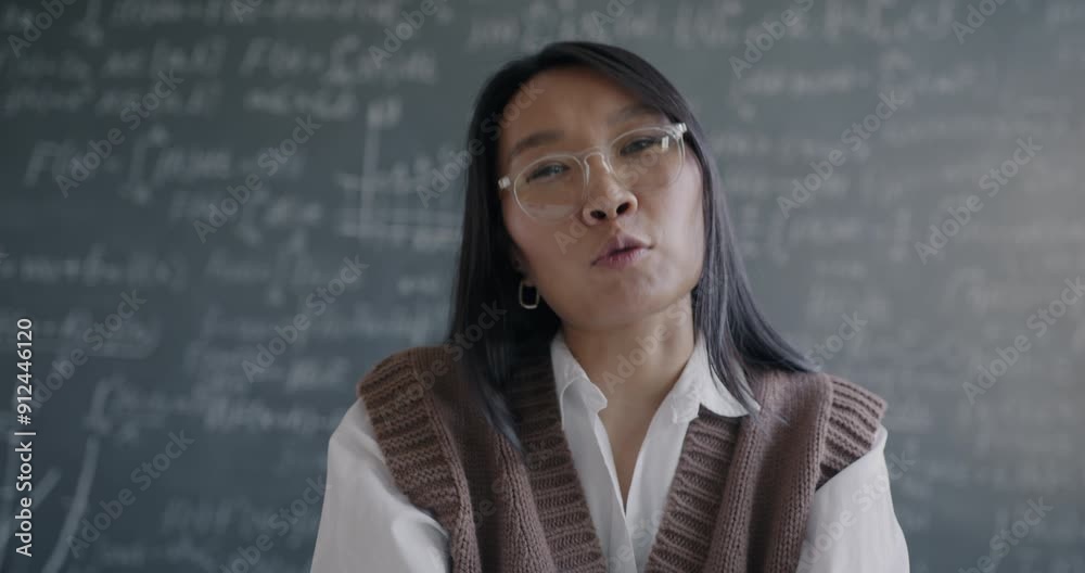 Portrait of Asian lady teacher chatting to student online speaking and looking at camera in classroom with chalkboard. Modern education and science concept. Portrait of Asian lady teacher chatting to student online speaking and looking at camera in classroom with chalkboard. Modern education and science concept.