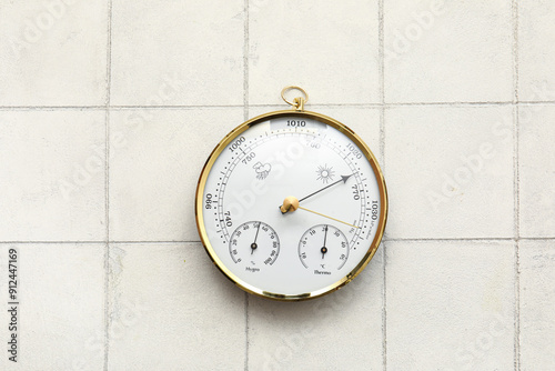 Aneroid barometer on white tiled background