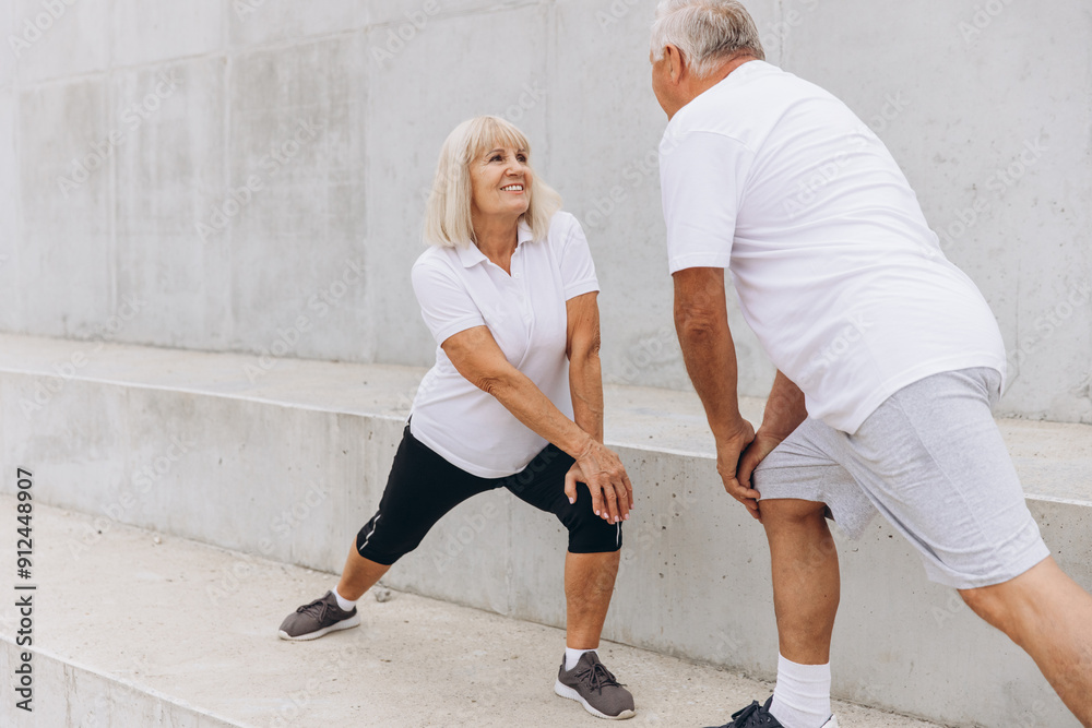 Senior Couple Exercising Together Outdoors in Matching Sportswear Senior Couple Exercising Together Outdoors in Matching Sportswear