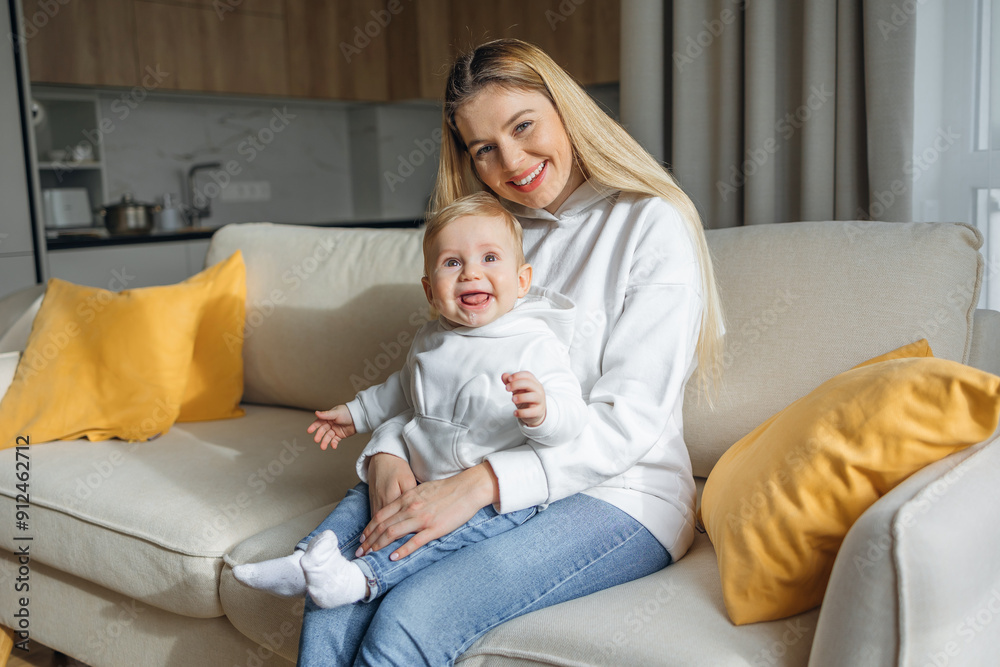 Happy Mother Holding Smiling Baby on Sofa at Home