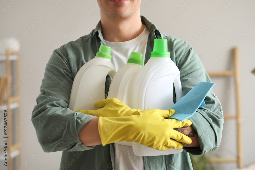 Young man with bottles of detergent and rag at home, closeup Young man with bottles of detergent and rag at home, closeup