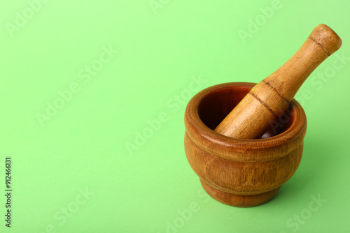 Wooden mortar and pestle on green background