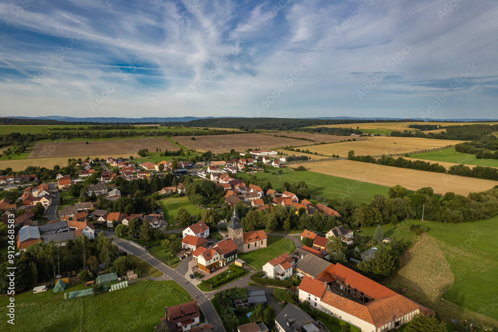 Aer ial view of a German village surrounded by meadows, farmland and forest. Thuringia, Germany.