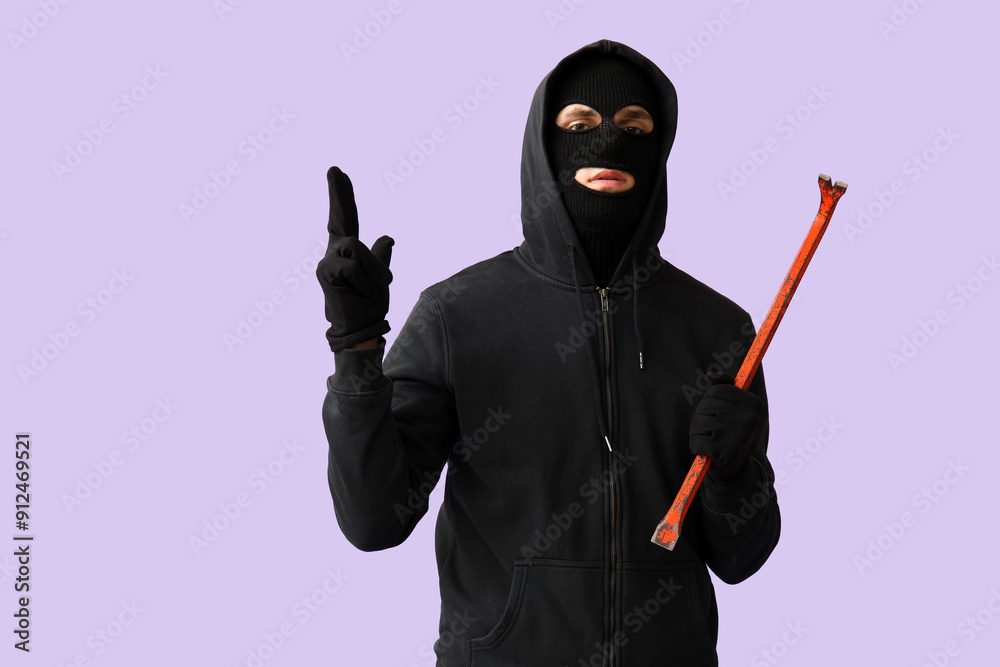 Male thief with crowbar showing gun gesture on lilac background Male thief with crowbar showing gun gesture on lilac background