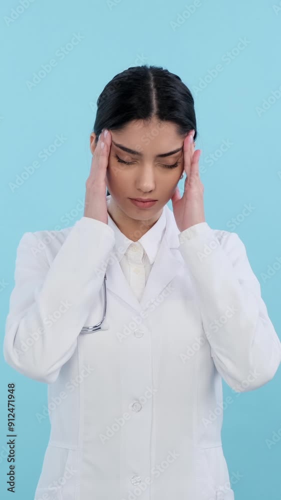 Unhappy and exhausted Caucasian female, young adult doctor or nurse suffering from headache or migraine on blue background. Vertical video. Unhappy and exhausted Caucasian female, young adult doctor or nurse suffering from headache or migraine on blue background. Vertical video.