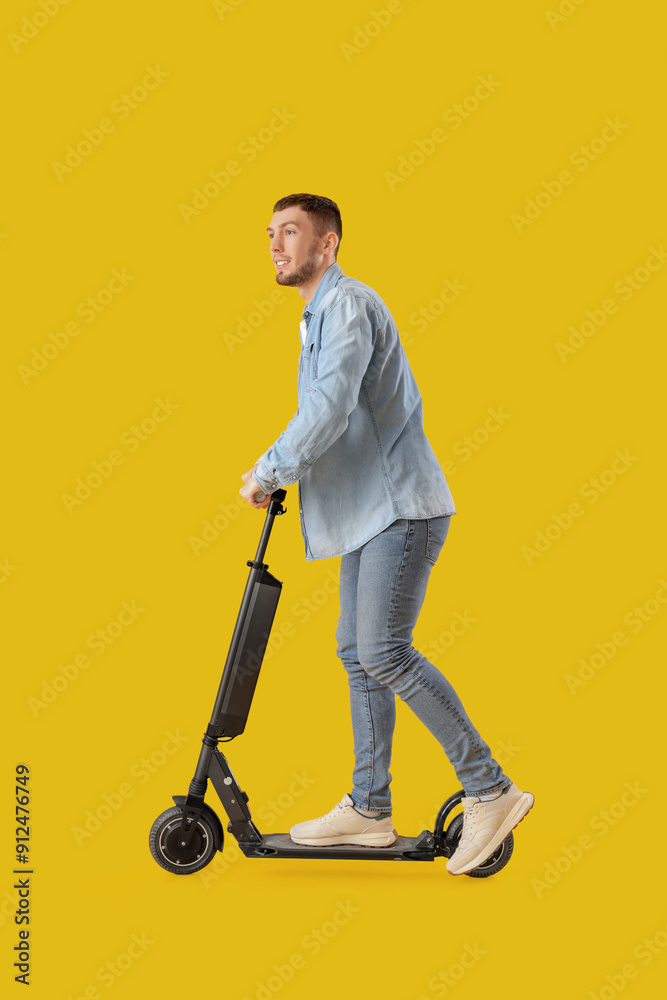 Young man riding electric scooter on yellow background Young man riding electric scooter on yellow background