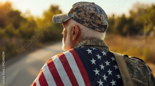 A senior military veteran in camouflage uniform draped in the American flag, standing outdoors at sunset, symbolizing patriotism.