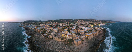Panoramic sunset view of Batroun, Lebanon, showcasing the coastal city's blend of ancient walls, modern buildings, and picturesque shoreline along the Mediterranean Sea