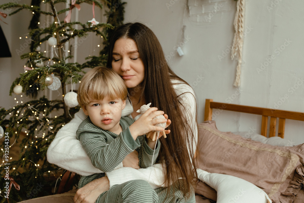 mother and son jump and have fun on the bed. the house is decorated for Christmas, Christmas tree and fir branches. New Year's decor